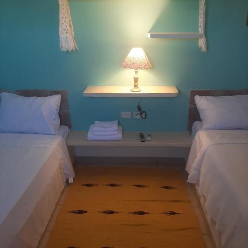 a room with two beds and a table with a lamp at Pousada Di Ponta in Goiana