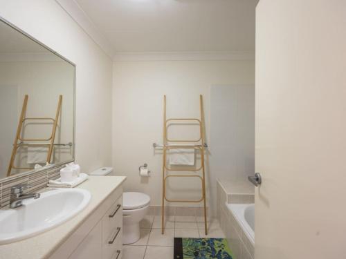 a bathroom with a sink and a toilet and a mirror at Cozy 3B2B Townhouse w Parking Backyard Malls and Parks in Rochedale South