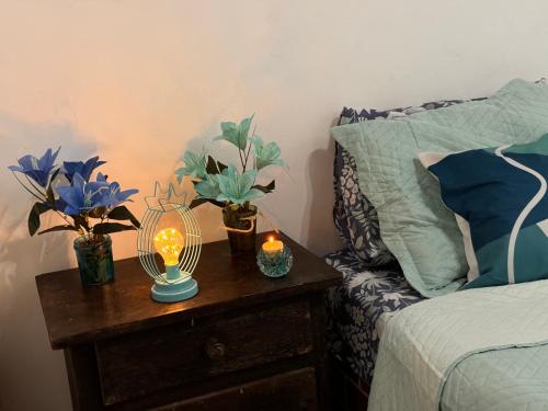 a nightstand with a lamp and flowers on it next to a bed at Pousada Casa de Buzios in Búzios