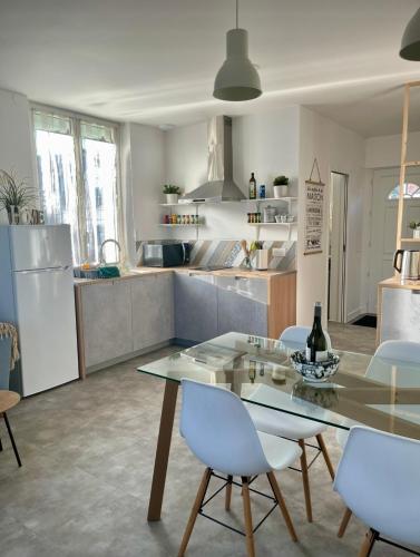 une cuisine avec une table en verre et des chaises blanches dans l'établissement Appartement cosy et calme avec parking et terrasse privés, à Cravanche