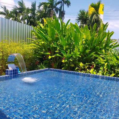 a swimming pool with a water fountain in a yard at Davy Cottage Phuket in Thalang