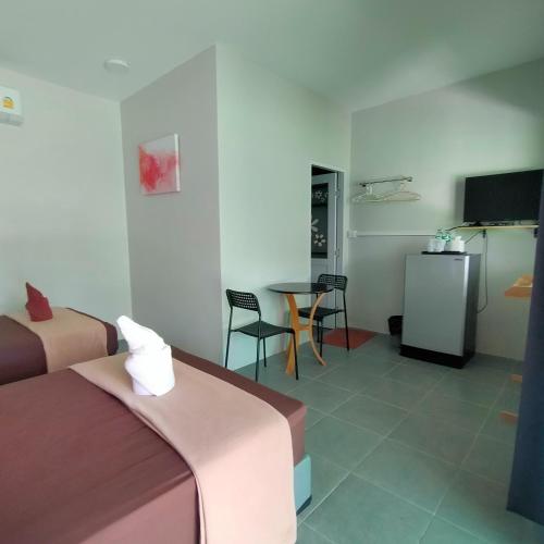a room with two beds and a table and a television at Davy Cottage Phuket in Thalang