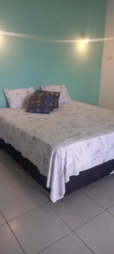a bed with a white bedspread and pillows on it at Pousada Di Ponta in Goiana