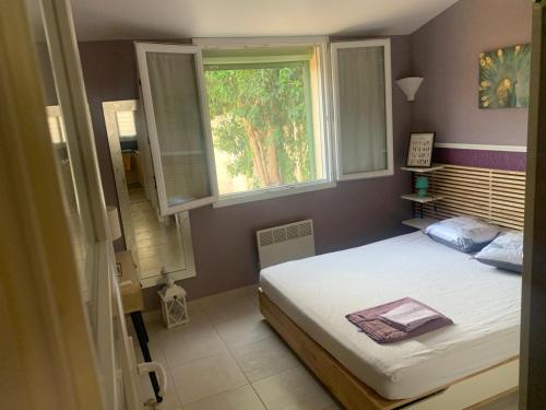 une petite chambre avec un lit et une fenêtre dans l'établissement Maison T2 Le cabanon Joli, à Istres