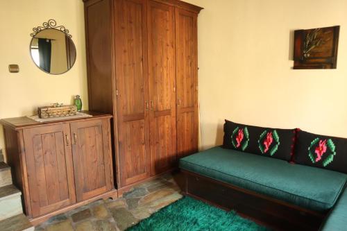 a living room with a green couch and a wooden cabinet at Gaea Mont Chalet in Palaios Agios Athanasios