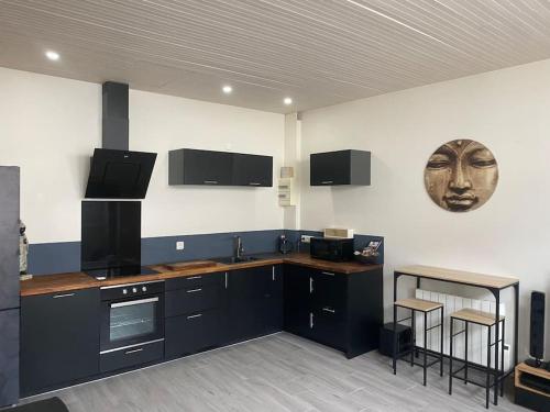 une cuisine avec des placards noirs et un masque mural dans l'établissement Appartement chaleureux avec terrasse en centre ville proche mer, à Saint-Nazaire