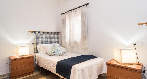 a bedroom with a bed with two lamps and a window at Finca Can Tiro in Costitx
