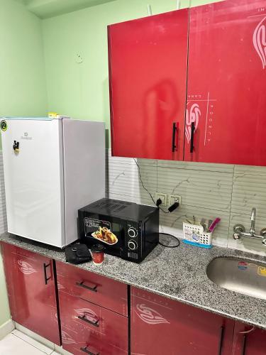 a kitchen counter with a microwave and a sink at Broadway Living in Rāmkot