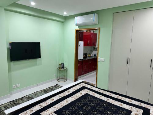 a room with a bed and a television on a wall at Broadway Living in Rāmkot