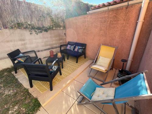 a patio with chairs and tables and a wall at Appartement Cosy avec extérieur au calme in Rocbaron