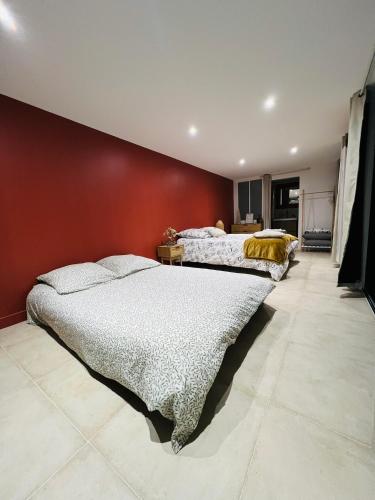 two beds in a room with a red wall at Villa du lac in Arsac