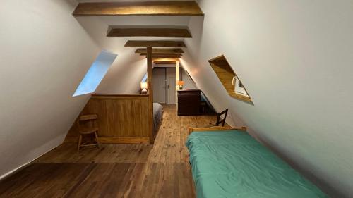 a bedroom with a green bed in a attic at Charmante maison de village in Condat-sur-Vézère