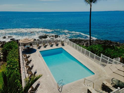 a swimming pool with chairs and the ocean in the background at The Alani at Kona Shores in Kailua-Kona