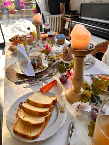 a table with a plate of bread and candles at La Grange Aux Hirondelles - Chambre familiale in Woignarue