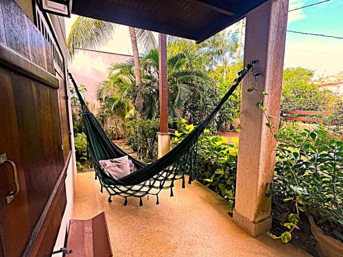 a hammock on the porch of a house at Casa Chalé dos Pássaros Guarajuba in Camacari