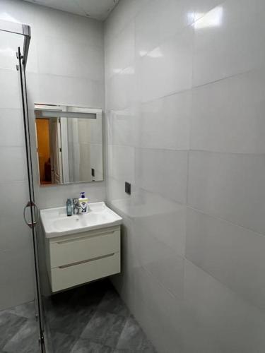 une salle de bains blanche avec un lavabo et un miroir dans l'établissement Qələbə Rezident, à Baku