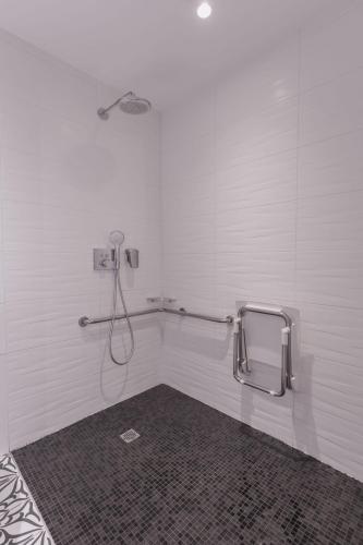 a bathroom with a shower in a white wall at Le Cornouaille Hotel & Spa in Bénodet