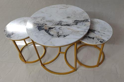 a marble table with two stools with gold legs at Gangi Kota East Flat in Kovvūr
