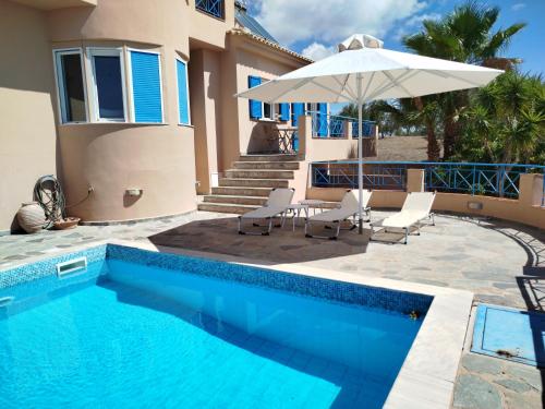 a house with a swimming pool and an umbrella at Tapia Hills in Methoni