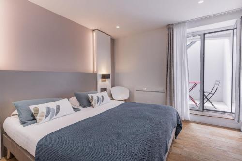 a bedroom with a large bed and a large window at Le Cornouaille Hotel & Spa in Bénodet