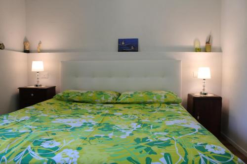a bedroom with a bed with a green comforter and two lamps at Condominio Le Dolomiti in Forni di Sotto