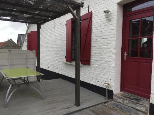 d'une terrasse avec des portes rouges et une table sur une terrasse couverte. dans l'établissement Gîte tout équipé au calme, à Saint-Amand-les-Eaux