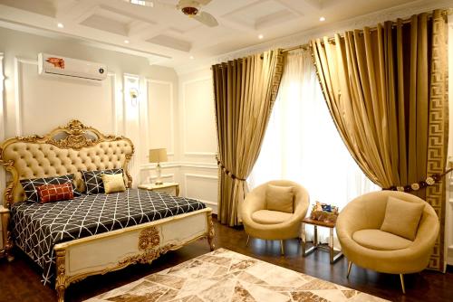 a bedroom with a bed and two chairs at Luxury Spanish Villa Close to Raya Fairways Commercial in Lahore