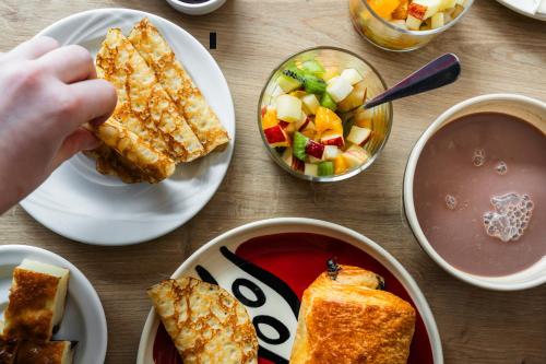 a table with plates of food and a person taking a piece of bread at Le Cornouaille Hotel & Spa in Bénodet