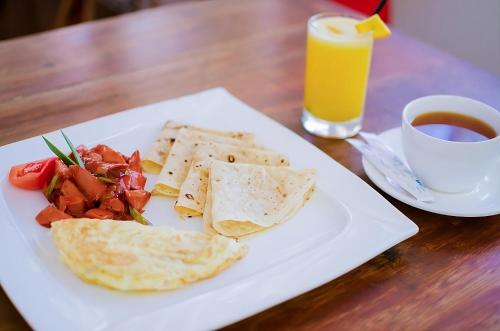 a plate of food on a table with a cup of orange juice at Hanifaru Beach Inn in Baa Atoll