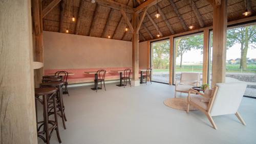 a large room with tables and chairs and windows at B&B Het Nagtegaaltje in Collendoorn