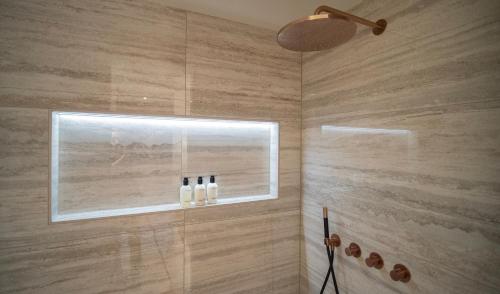 a bathroom with a shower with three bottles on a window at B&B Het Nagtegaaltje in Collendoorn