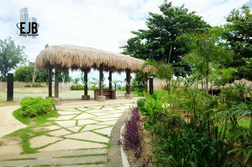 a pavilion with a grass roof and a path at Mactan Newtown Beach Condo in Mactan