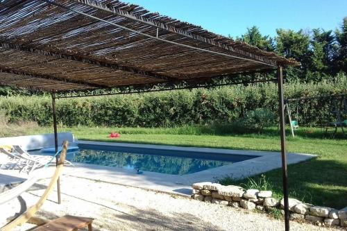une pergola au-dessus d'une piscine dans une arrière-cour dans l'établissement Beau mas en campagne de l'Isle sur la Sorgue, à LʼIsle-sur-la-Sorgue