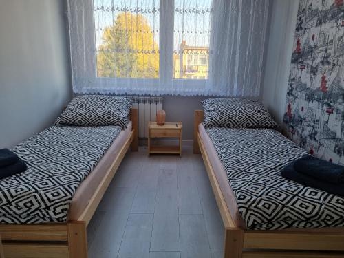 two twin beds in a room with a window at Apartament DOBRA NOCKA in Ostróda