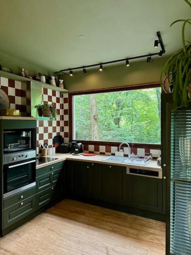 une cuisine avec un évier et une grande fenêtre dans l'établissement LA FEUILLÉE, Charmante Maison au Bois de Cise, à Ault