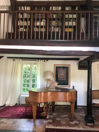 a wooden piano in a living room with a table at La Chalonnière in Châlo-Saint-Mars