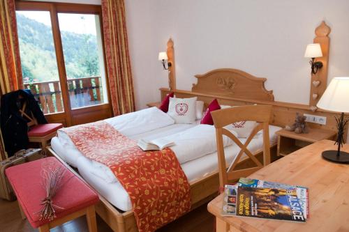 a bedroom with a bed and a table and a window at Logis Auberge Du Mehrbachel - Hôtel & Restaurant in Saint-Amarin