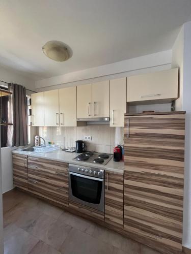 a kitchen with wooden cabinets and a stove top oven at Apartments Marinić in Tivat