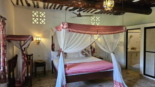 a bedroom with a canopy bed with pink sheets at Amani Paradise - Luxury Villas in Diani Beach