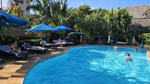 a group of people swimming in a swimming pool at Amani Paradise - Luxury Villas in Diani Beach