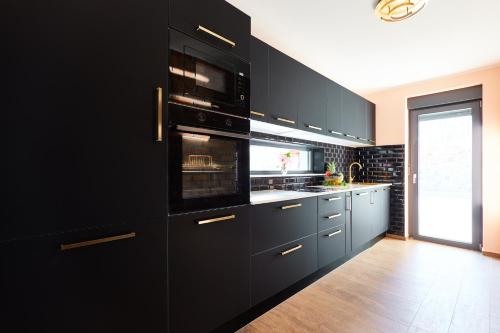 a kitchen with black cabinets and an oven at Vila Tia in Karlovac