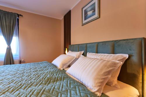 a bedroom with a bed with white pillows and a window at Vila Tia in Karlovac