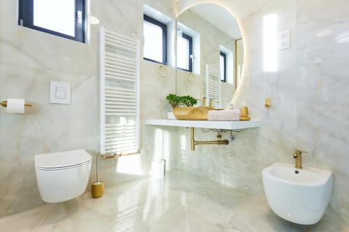 a white bathroom with a toilet and a sink at Vila Tia in Karlovac