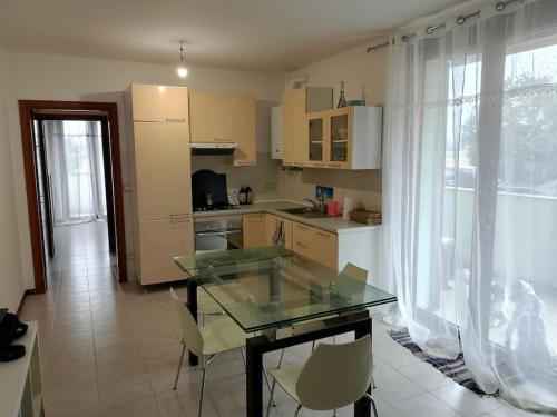 a kitchen with a glass table and white cabinets at bilocale con giardino in Zibido al Lambro