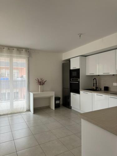 une cuisine avec des placards blancs et une grande fenêtre dans l'établissement Superbe Appartement - Near Paris, à Corbeil-Essonnes