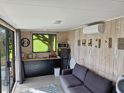 ein Wohnzimmer mit Couch und Küche in der Unterkunft Twin Totara Cottage in Mangawhai