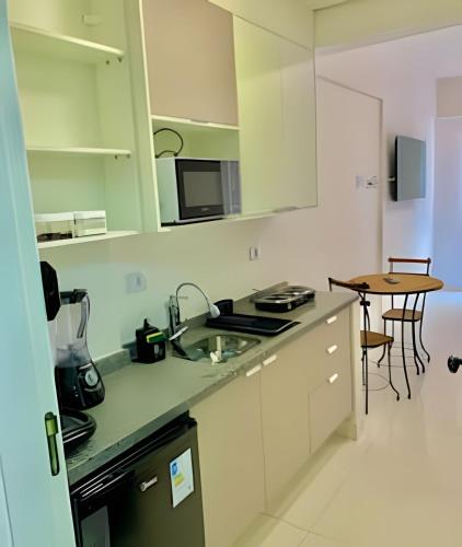 a kitchen with white cabinets and a sink and a table at Studio Vertentes in Sao Paulo