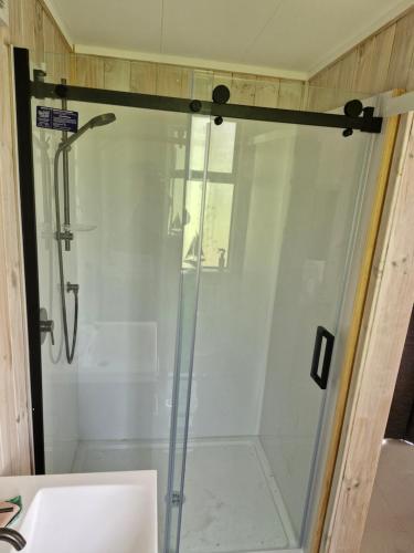 eine Dusche mit einer Glastür in einem Badezimmer in der Unterkunft Twin Totara Cottage in Mangawhai