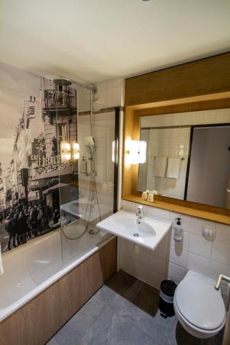 a bathroom with a sink and a tub and a toilet at Campanile Prime Paris 19 - La Villette in Paris