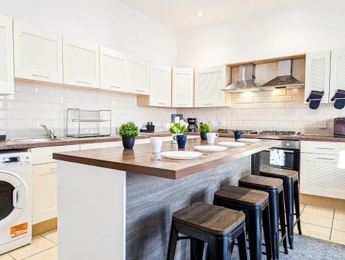 a kitchen with white cabinets and a counter with stools at Central Southsea Guest House in Portsmouth